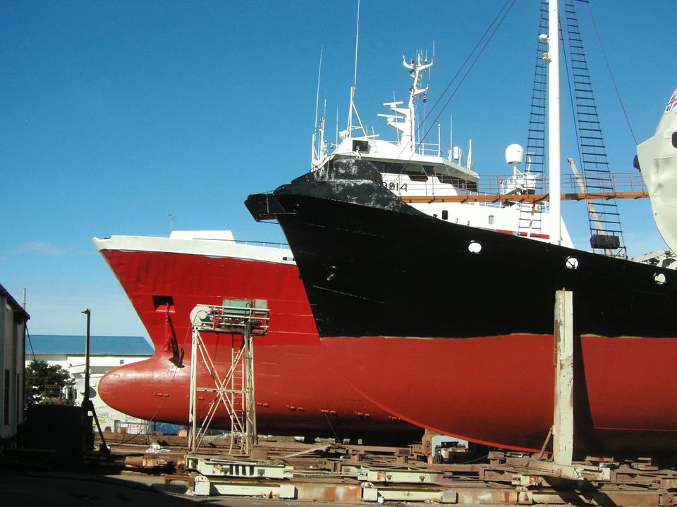 Large black and red ships docked on dry land under a clear blue sky