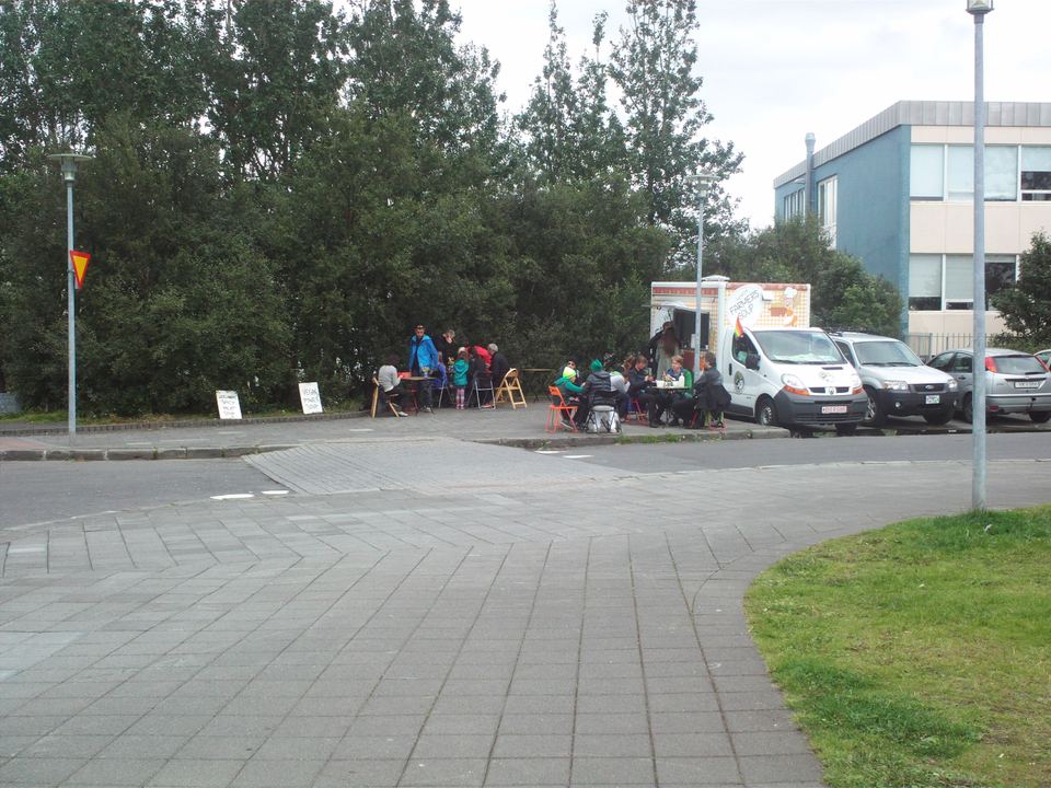 People sitting at outdoor tables near a soup food truck in Reykjavik.