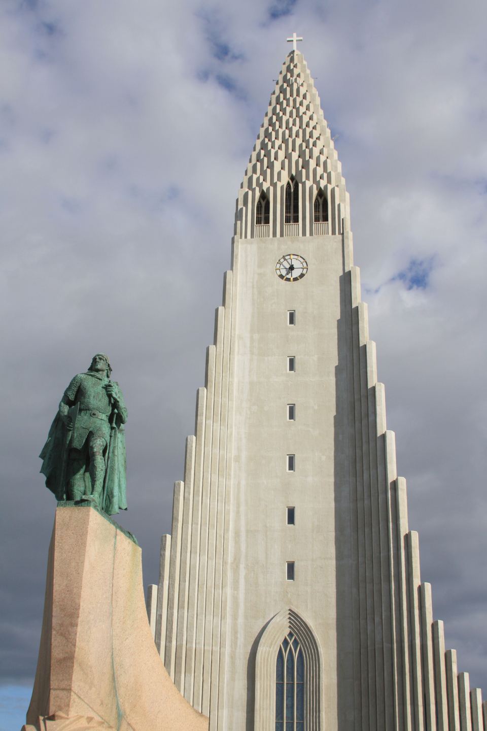 The towering concrete facade of Hallgrímskirkja church stands behind a statue of Leif Erikson.