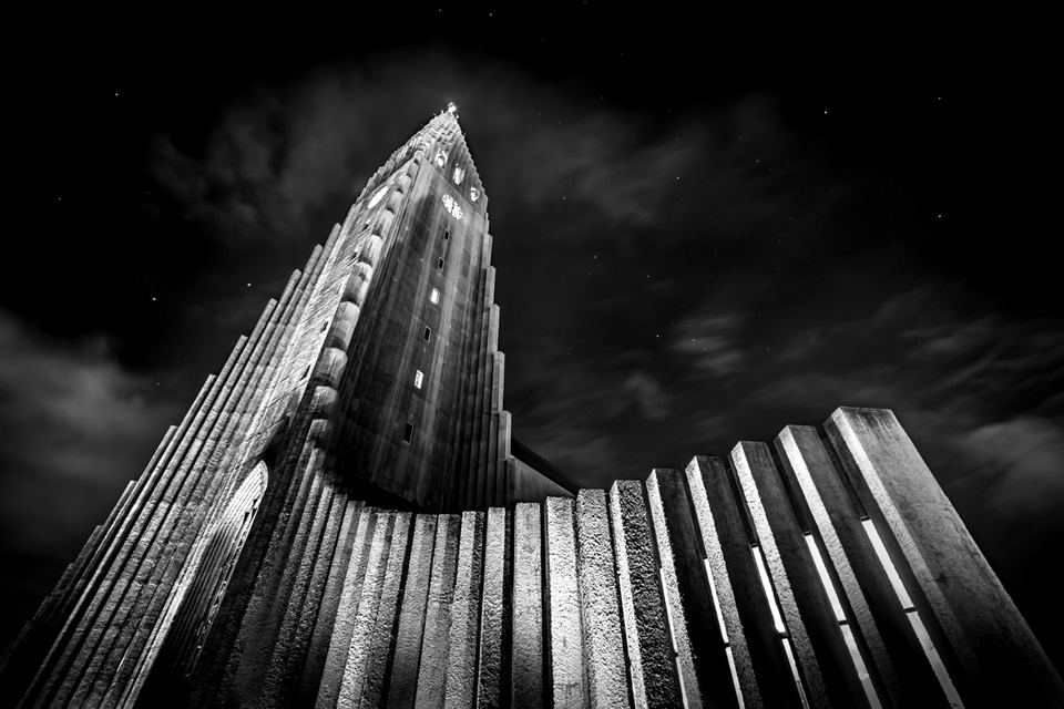 Black and white photograph looking up at the illuminated facade of Hallgrímskirkja church at night