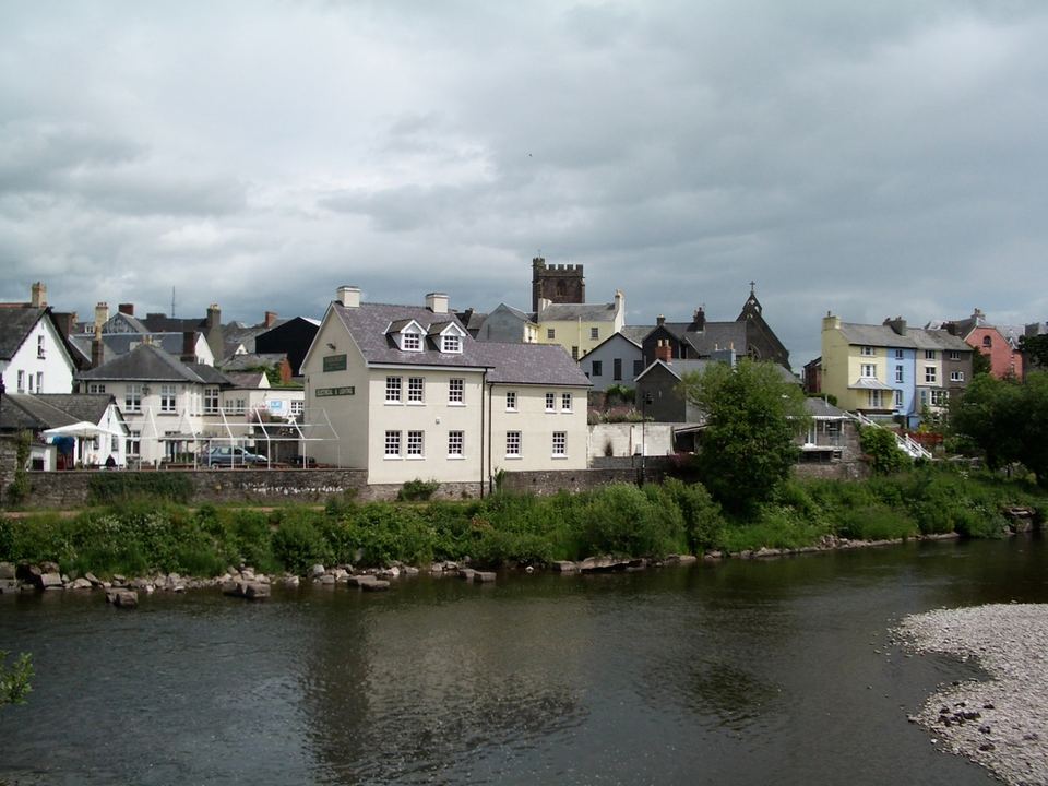 Row of traditional British buildings along a calm river under an overcast sky.