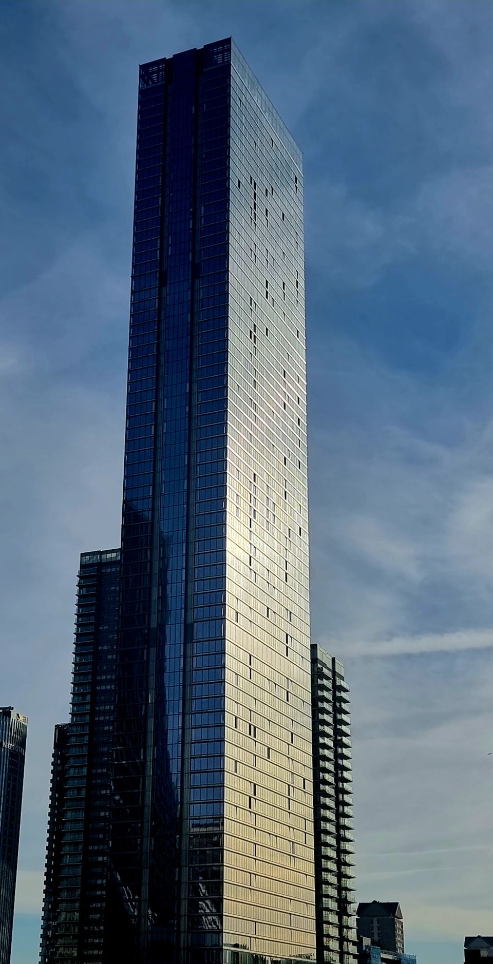 A tall modern glass skyscraper standing against a bright sky