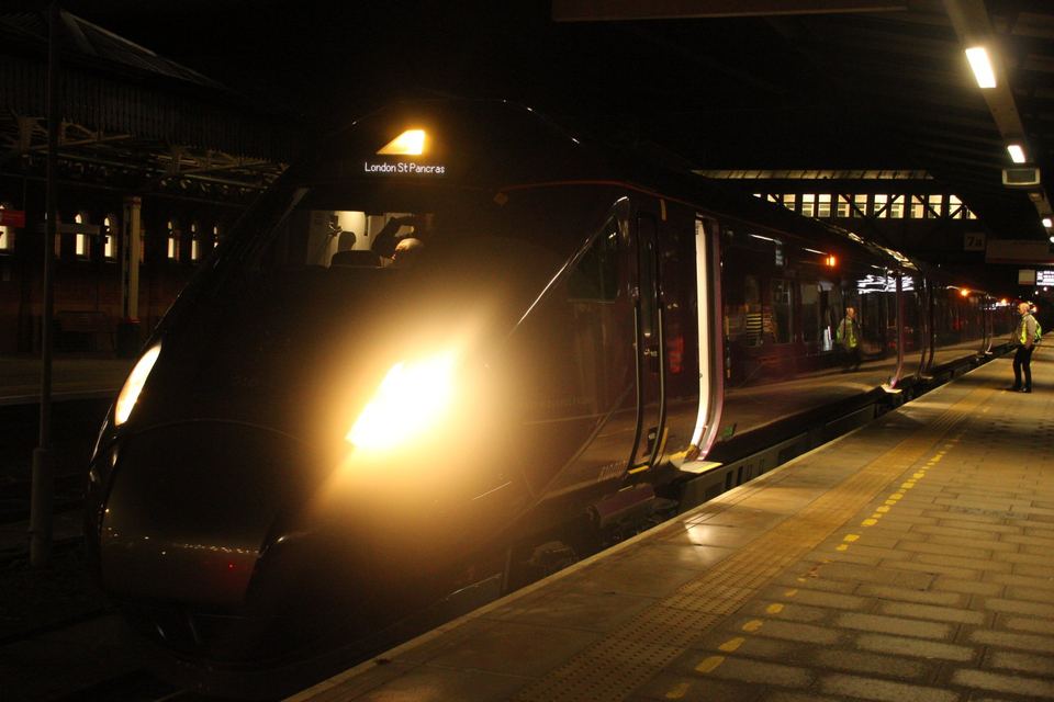 A sleek passenger train parked at a station platform at night