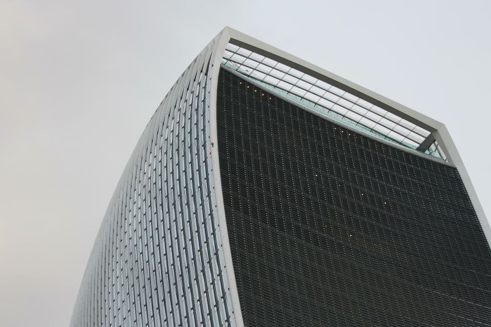 Low angle view of a modern curved skyscraper against a gray sky