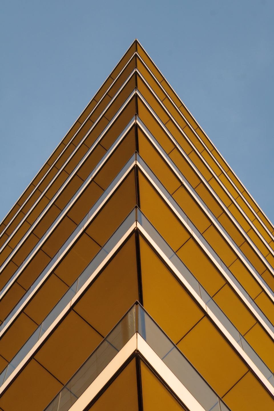 Low angle view of a modern building with yellow balconies against a blue sky