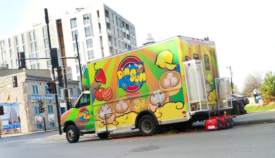 Side profile of a colorful food truck parked near an urban intersection.