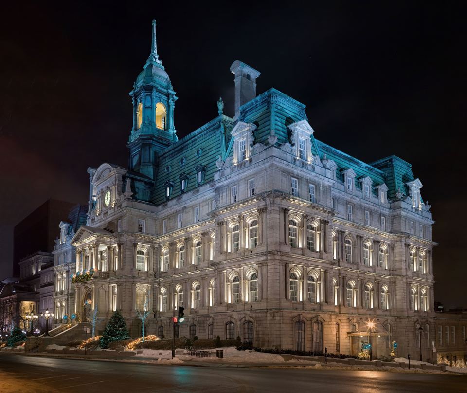 Historic Montreal City Hall building illuminated with blue light at night