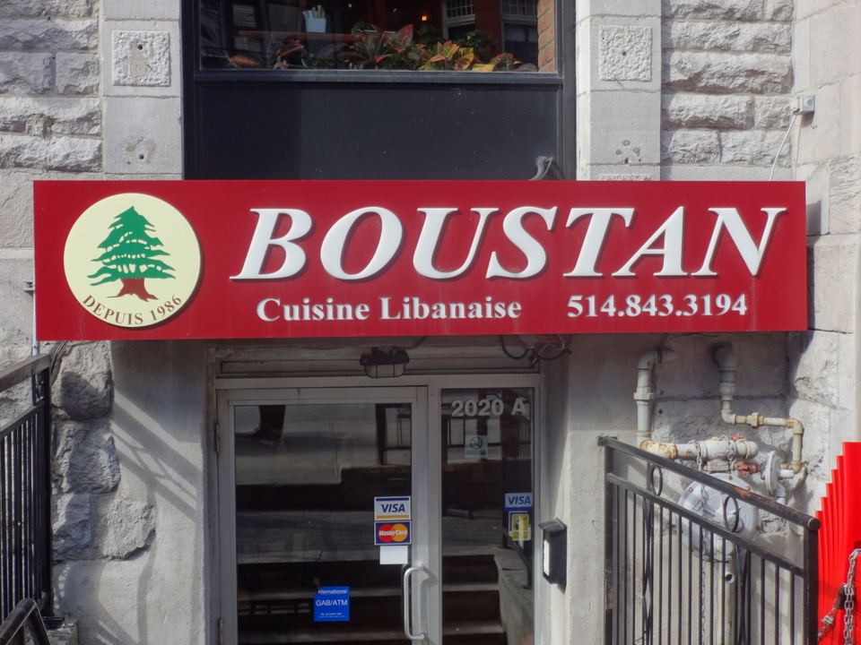 A close-up view of a red restaurant banner above a basement entrance door.