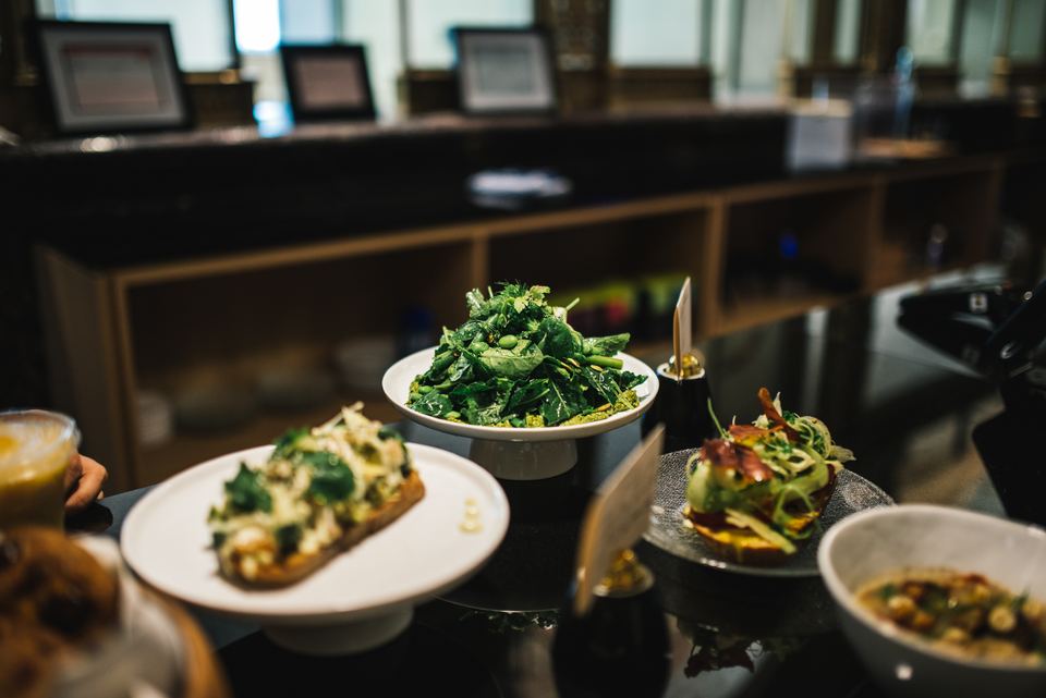 Fresh green salad and avocado toast on white plates placed on a cafe counter