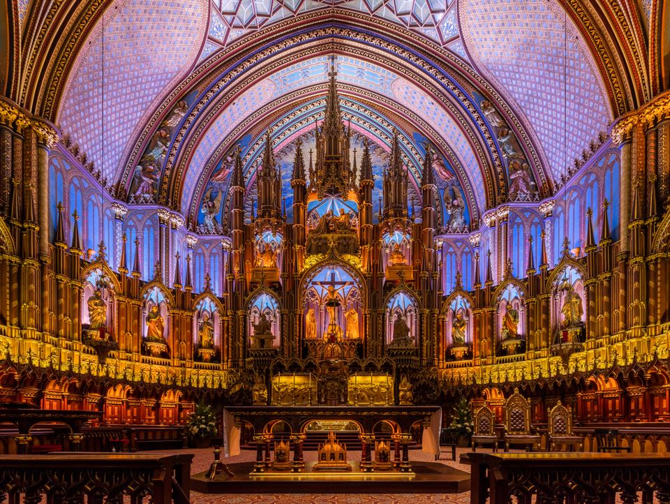 Gilded altar and detailed sanctuary interior illuminated in blue light inside Notre-Dame Basilica