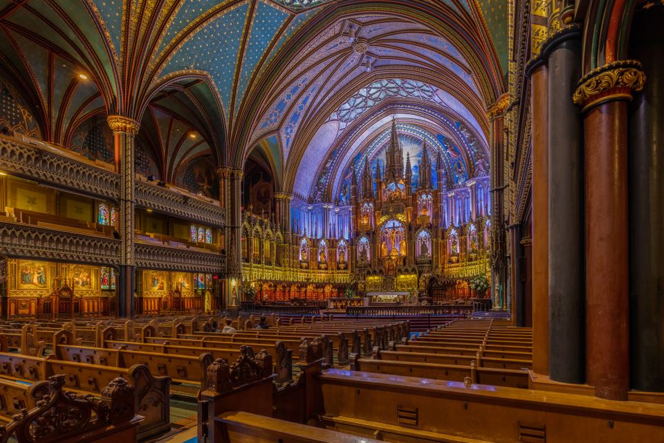 Wide interior view of Notre-Dame Basilica showing wooden pews and glowing altar