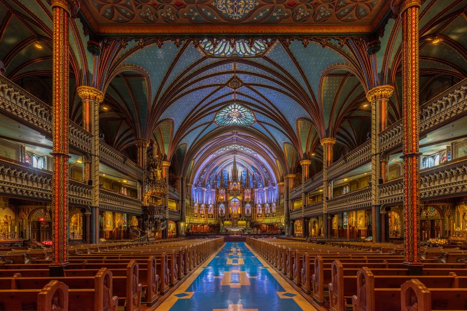 Symmetrical view down a church nave towards a glowing blue and gold altar.