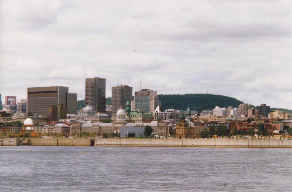View across the water toward historic city buildings backed by a lush green hill