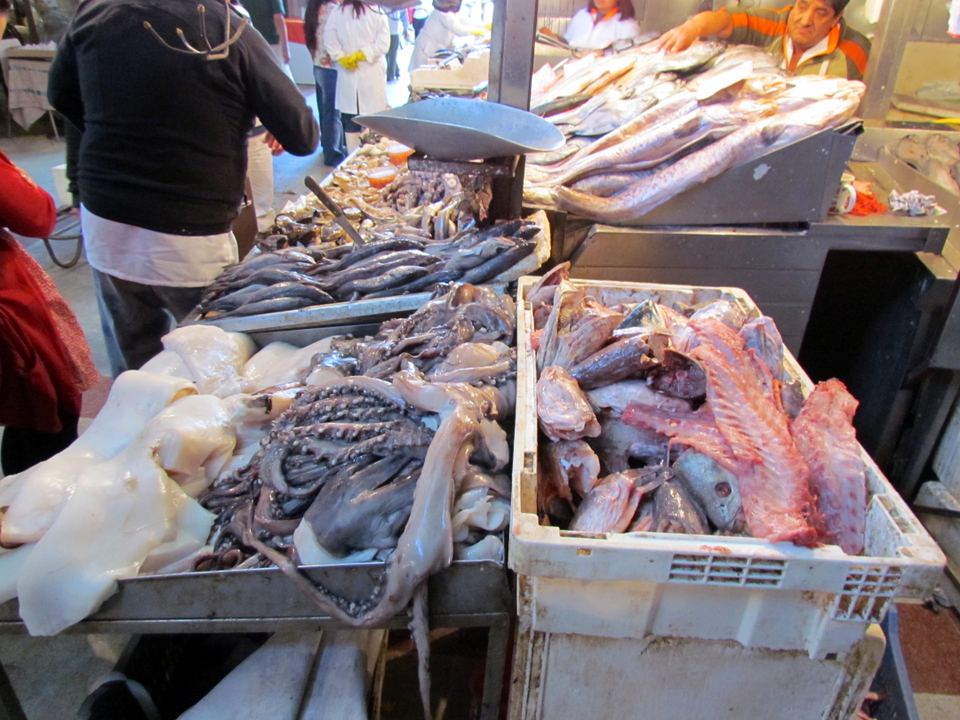 Fresh seafood including octopus and whole fish on display at a market stall