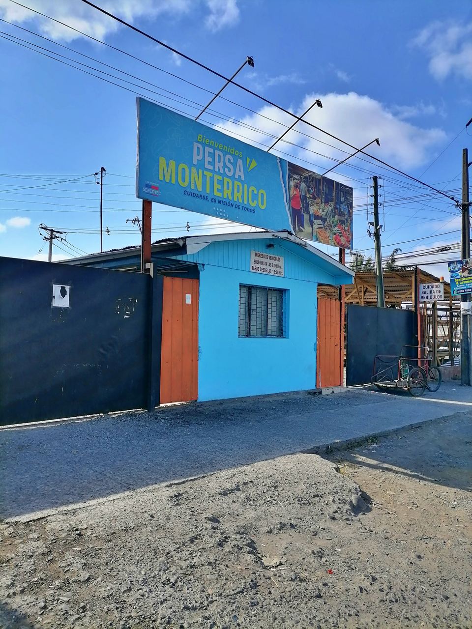 A blue market entrance with a large sign under a blue sky