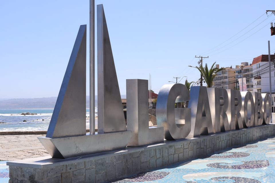 Large metal letters spelling out Algarrobo on a coastal promenade in Chile.