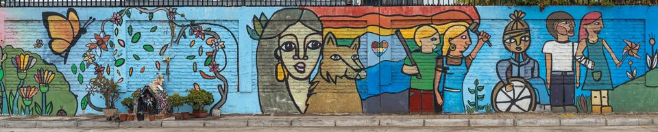Panoramic view of a colorful street mural along a sidewalk wall
