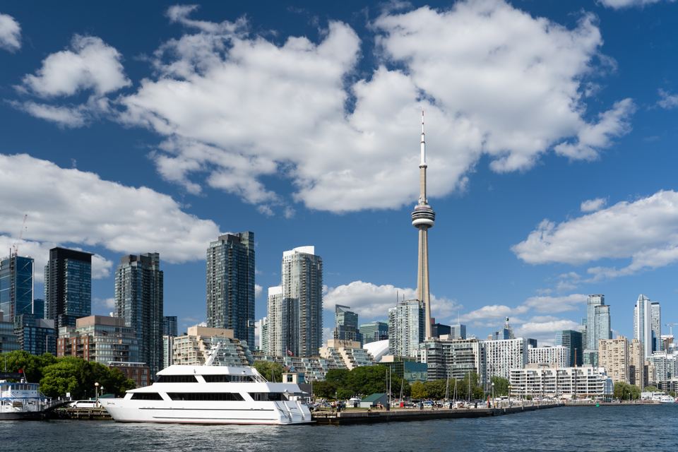 A white cruise boat docked in Toronto harbor with the downtown skyline in the background
