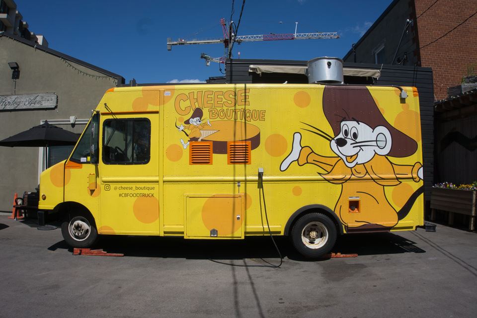 Side view of a vibrant yellow food truck decorated with a cartoon mouse mascot.
