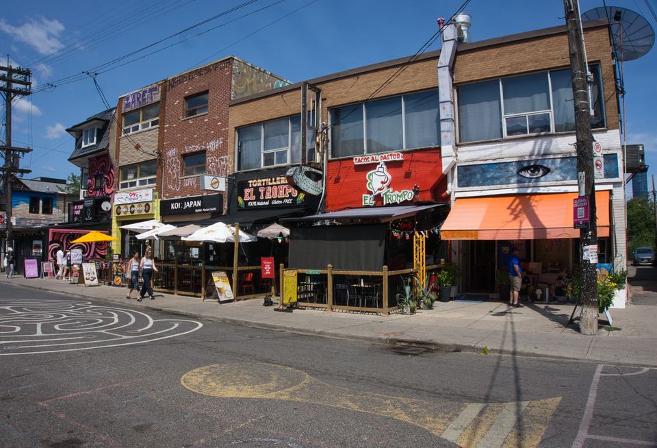 Bright street view of Mexican and Japanese eateries with patio umbrellas along a sidewalk