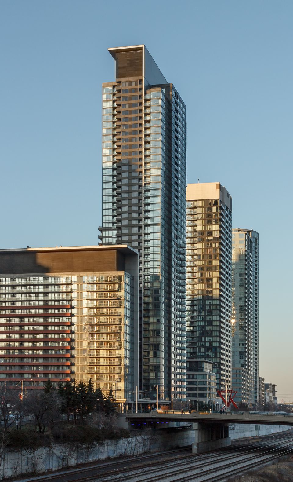 Tall modern glass apartment towers standing under a clear blue sky during late afternoon.