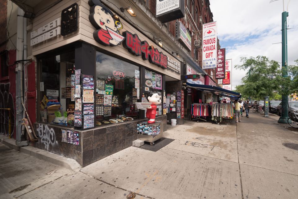 Exterior view of a corner ramen shop with Japanese signage and menu posters