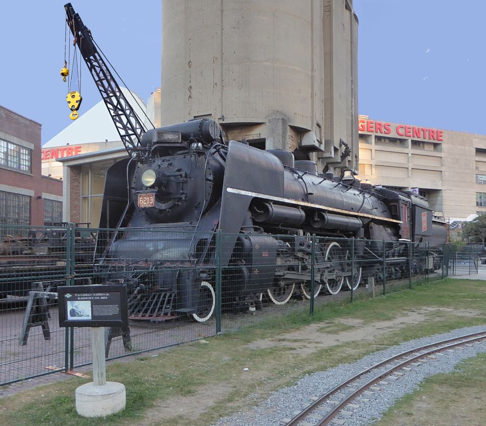 A black vintage steam locomotive parked outside in front of the Rogers Centre building