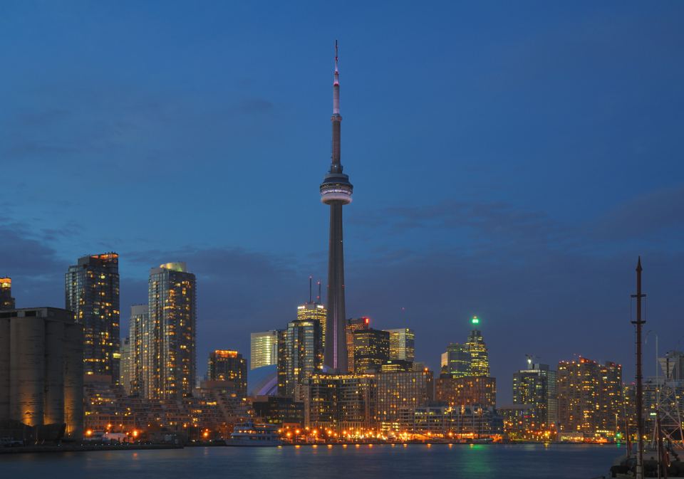 Toronto skyline with the illuminated CN Tower standing out against the dusk sky over water