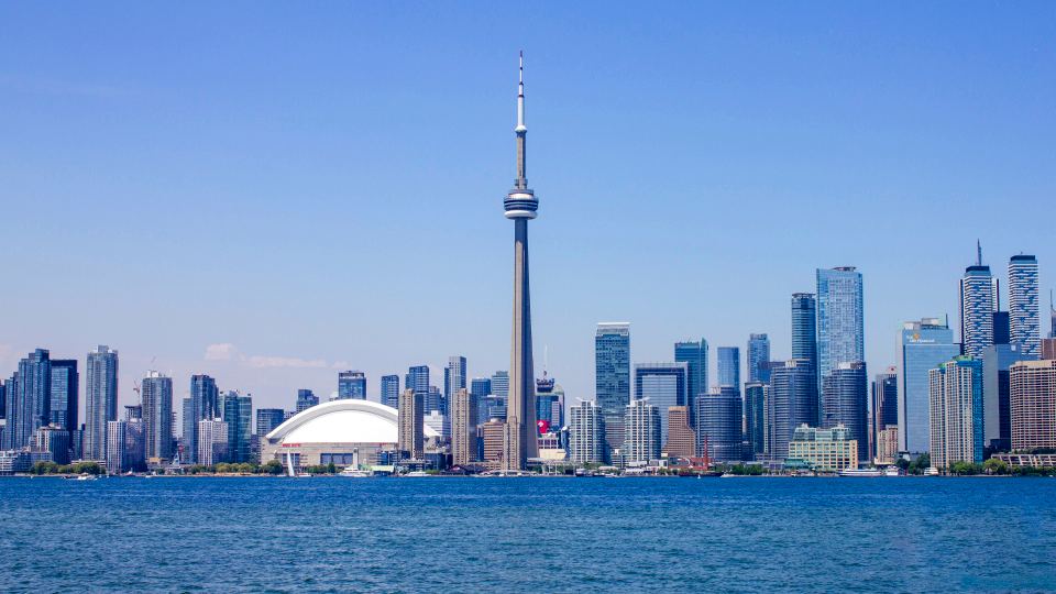 Panoramic view of the Toronto skyline featuring the CN Tower across blue lake water
