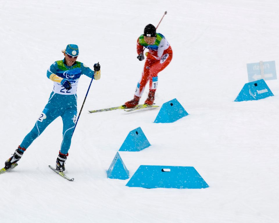 Two athletes competing on a snow-covered cross-country skiing track.