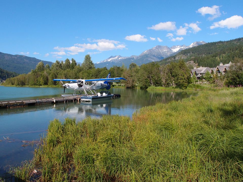 Blue and white floatplane docked on a calm mountain lake in Whistler