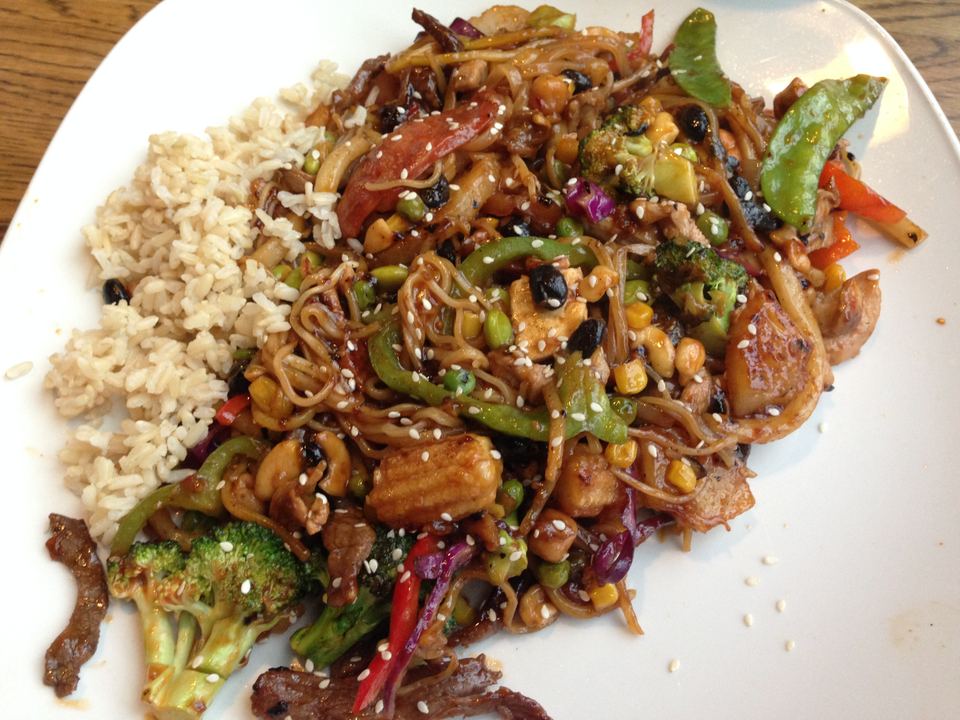 A white plate filled with stir-fried noodles, vegetables, and rice.