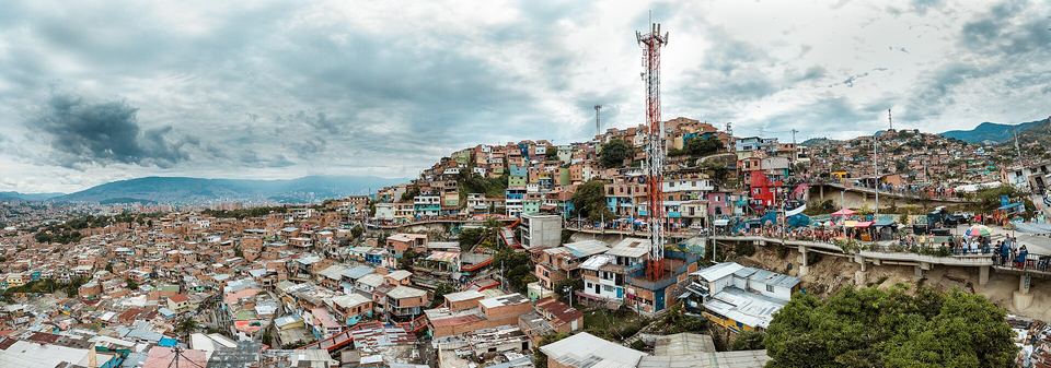Panoramic view of colorful hillside houses and elevated walkways in Comuna 13, Medellín.