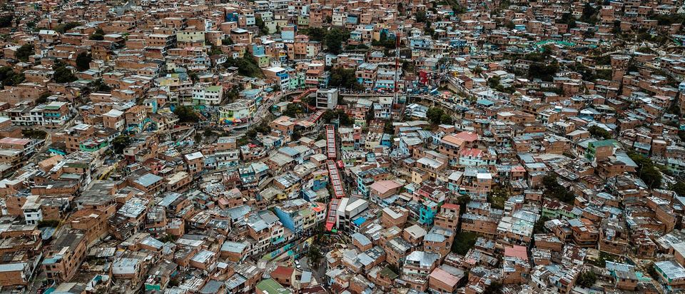 High-angle aerial view of densely packed brick houses and outdoor escalators in Comuna 13.