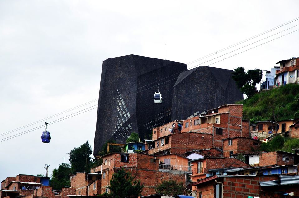 The dark angular blocks of the Biblioteca Espana above Metrocable cables and hillside houses