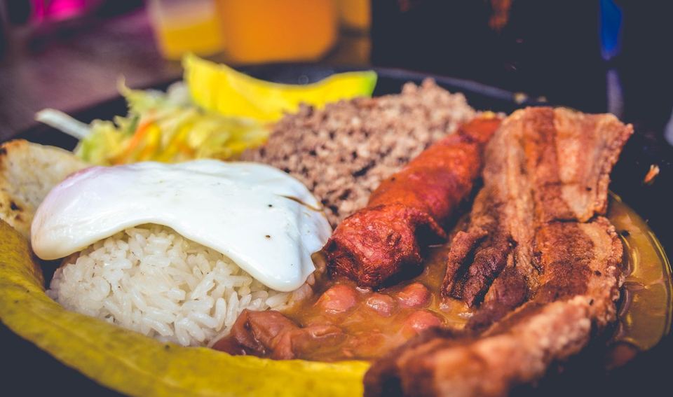 A bandeja paisa with beans, rice, chicharron, plantain, avocado and a fried egg