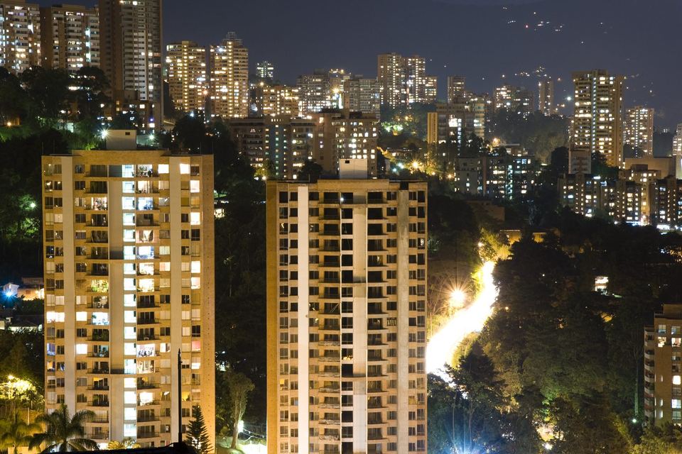 Lit apartment towers on the wooded hillside of El Poblado, Medellin, after dark