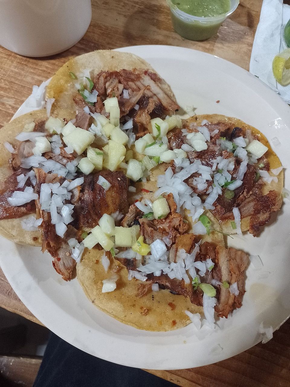 A plate of tacos al pastor with onion, coriander and pineapple