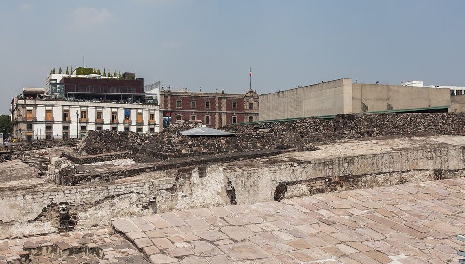 The excavated stone platforms of the Templo Mayor beside colonial buildings