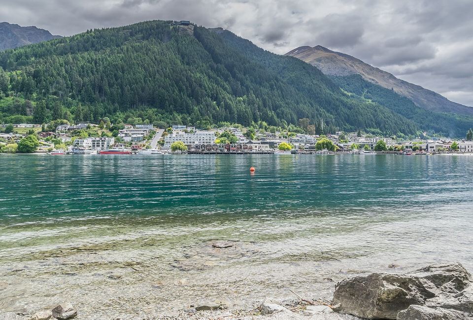 Boats moored in Queenstown Bay with mountains filling the horizon.