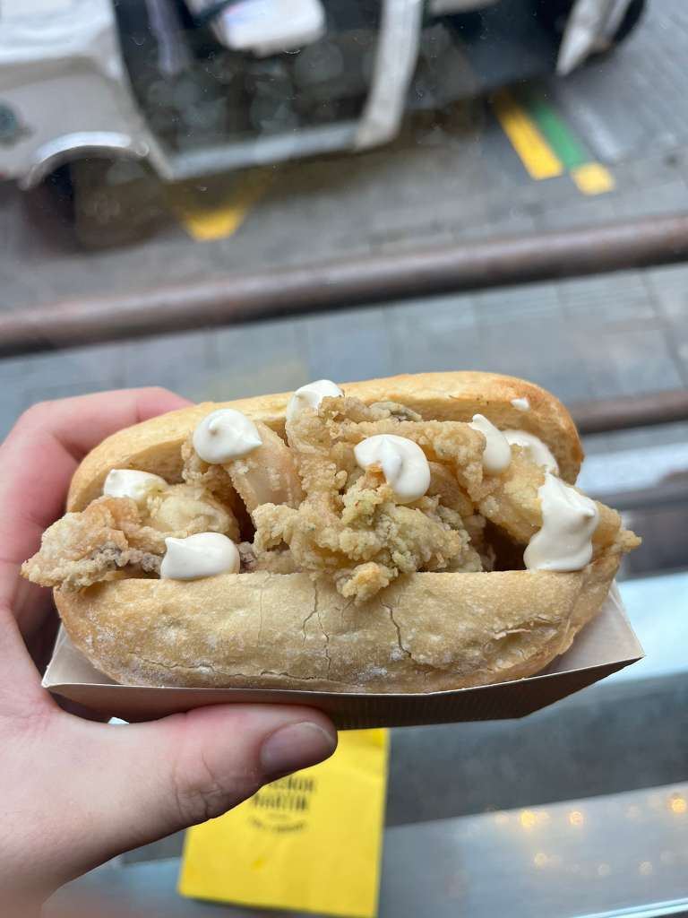 A crusty bread roll filled with crispy fried squid rings and topped with garlic aioli.