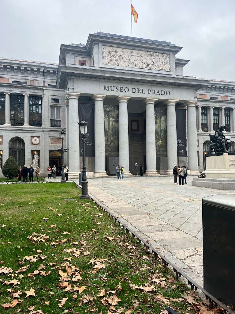 Exterior view of the Museo del Prado building with grand stone columns under a cloudy sky.