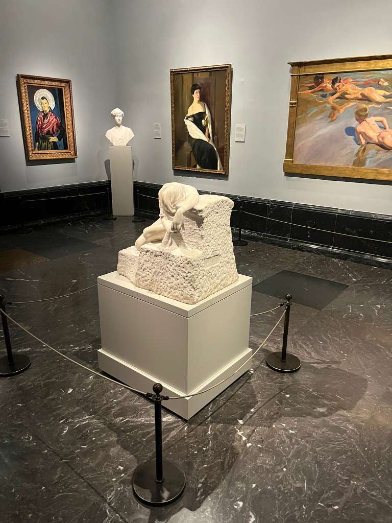 Museum room displaying beach scene paintings by Sorolla and a bowed marble sculpture.