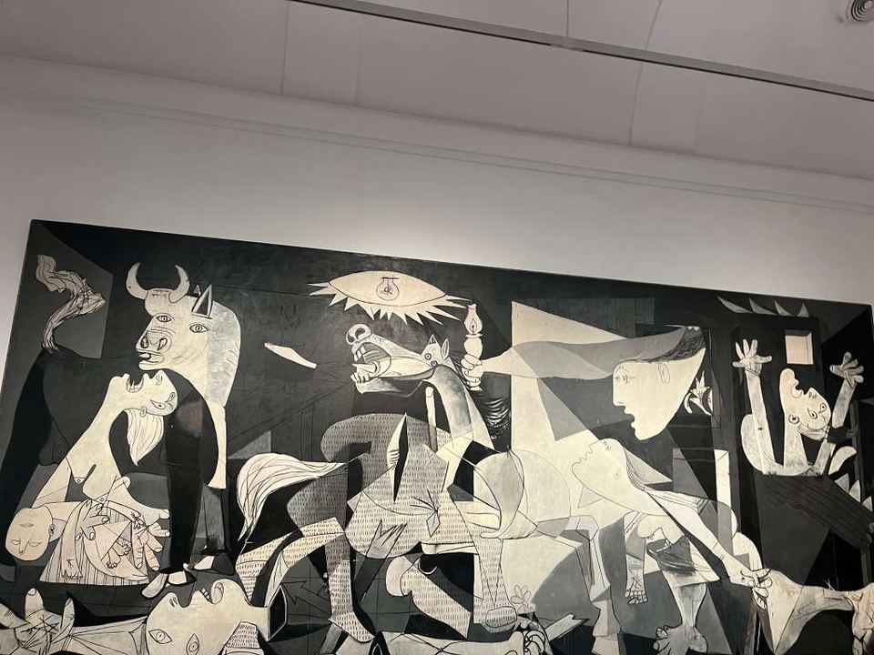 A wide black-and-white mural with cubist figures of a horse, bull, and weeping women.