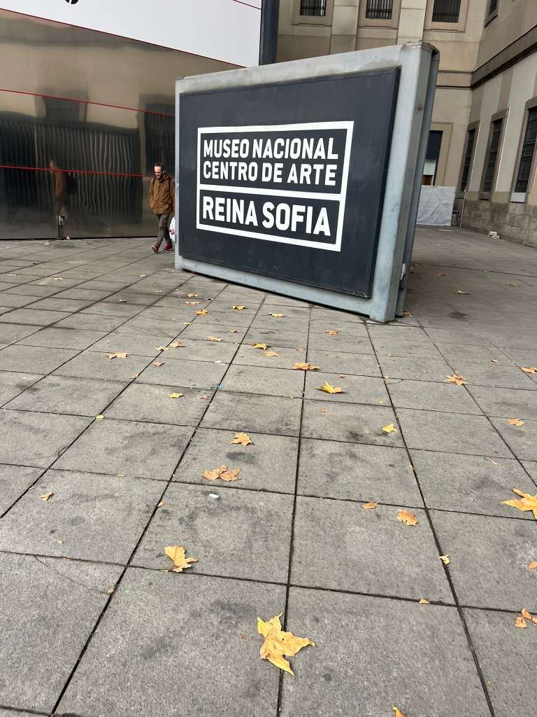 A black entrance sign for the Museo Nacional Centro de Arte Reina Sofia on a paved plaza.