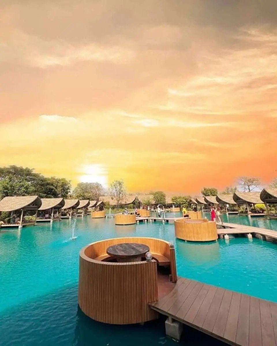 Circular wooden cabana seating set in a turquoise lagoon at sunset at Bubble in the Forest Cafe