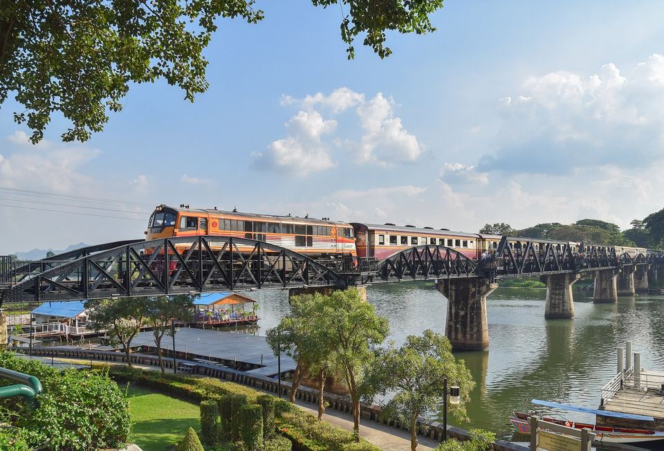 A tourist train crossing the black steel Bridge over the River Kwai at Kanchanaburi