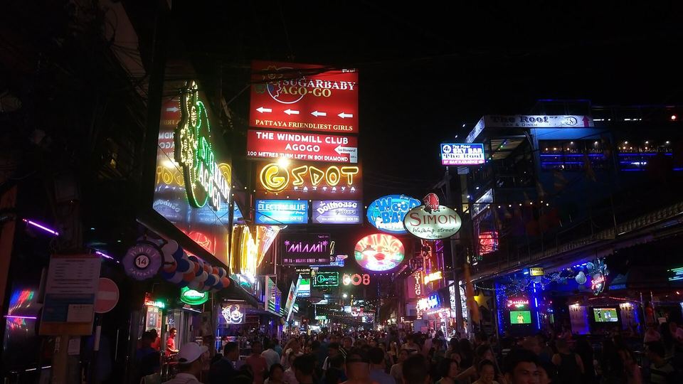 Neon bar signs and crowds along Walking Street in Pattaya at night, photographed from the street