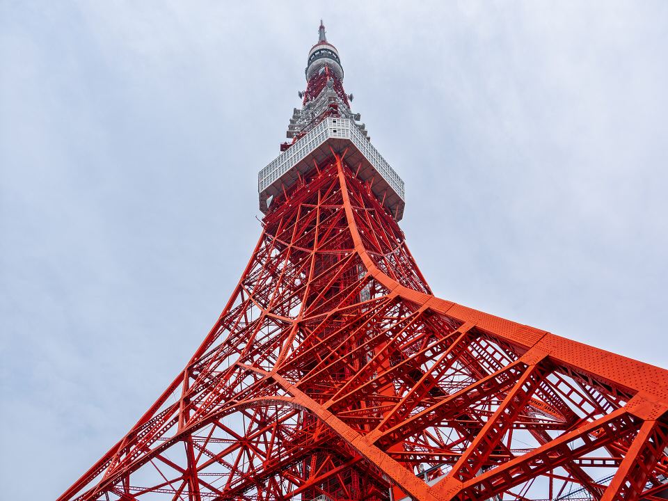 Low-angle view looking up at the red and white steel structure of Tokyo Tower.
